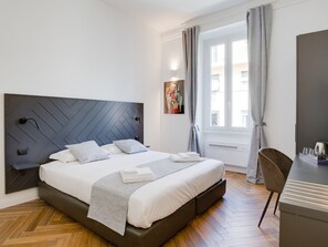 A modern bedroom with a large bed, a desk, and a window with curtains. - The Right Place (Rome)