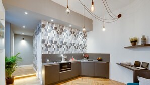 A modern kitchen with a herringbone wood floor, a built-in oven, and a grey island with a geometric backsplash. - The Right Place (Rome)
