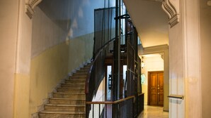 A grand staircase with marble steps and a black metal railing, leading to an upper floor. - The Right Place (Rome)