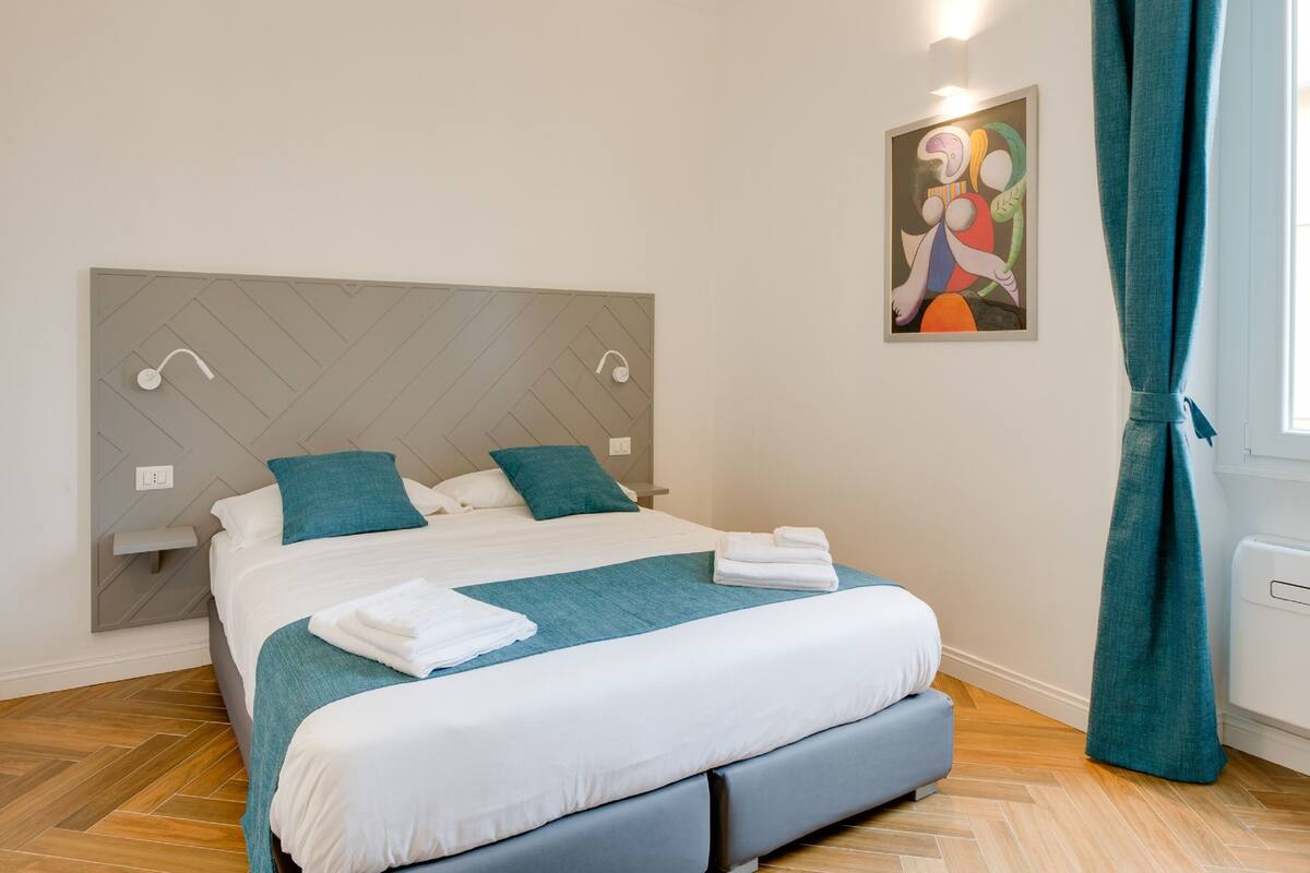 Una camera da letto moderna con un letto, una testiera, comodini e un quadro appeso al muro.