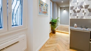 A modern interior with a herringbone floor, a radiator, a potted plant, a painting, and a geometric-patterned wall. - The Right Place (Rome)