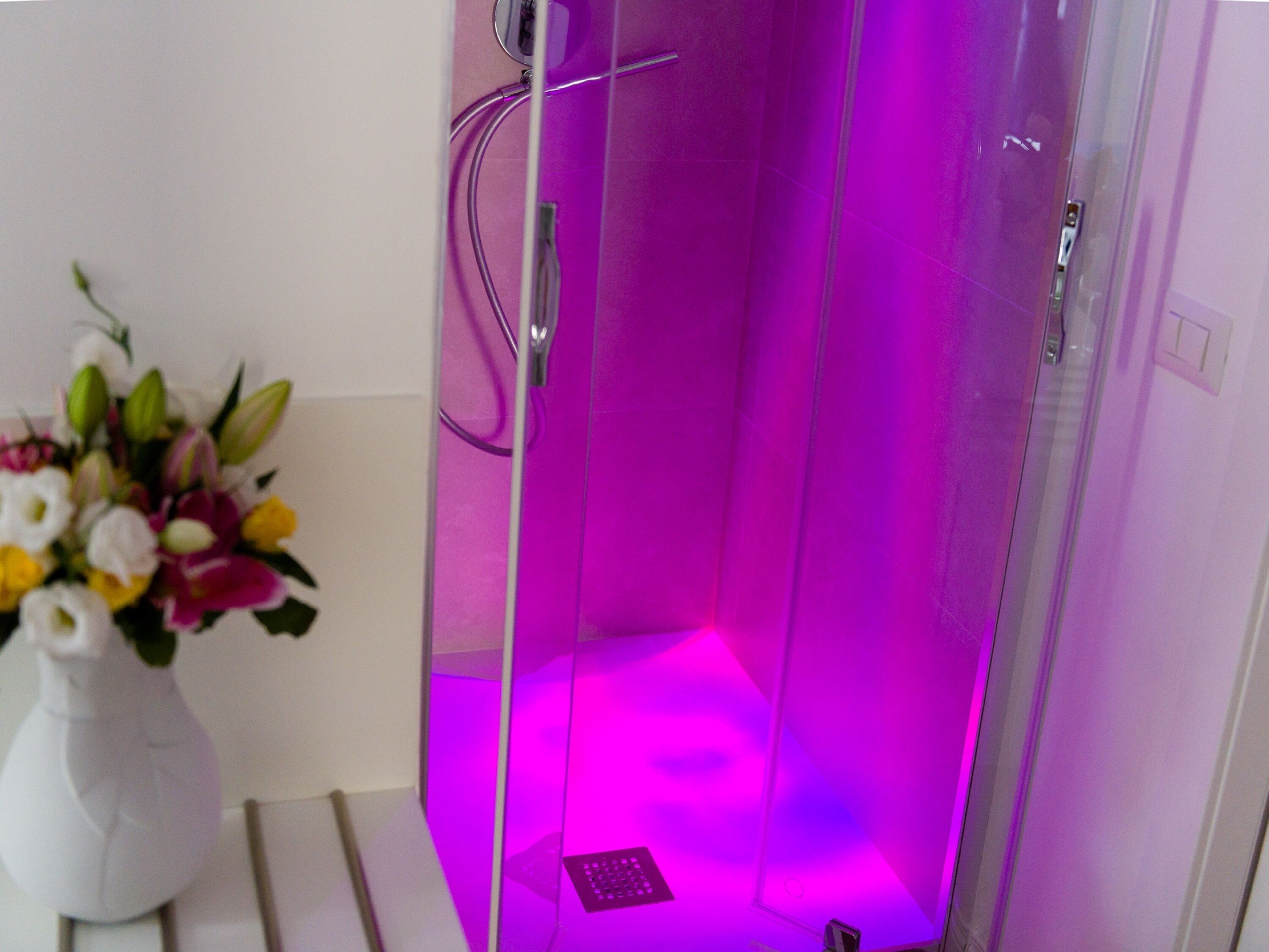 A modern bathroom with a glass enclosure, a showerhead, and a small sink.