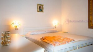 Un dormitorio con una cama, dos lámparas de noche, un cuadro pequeño en la pared y un jarrón decorativo con forma de concha.