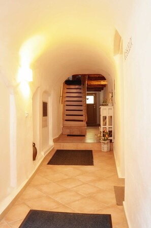 A hallway with a wooden staircase, a white cabinet with flowers, and a door at the end. - Neisse - Old town house/holiday apartments Görlitz (Görlitz)