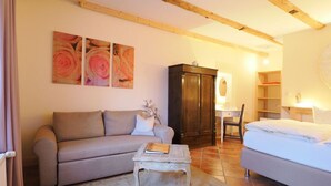 Una sala acogedora con sofá, mesa de centro, aparador y cama.