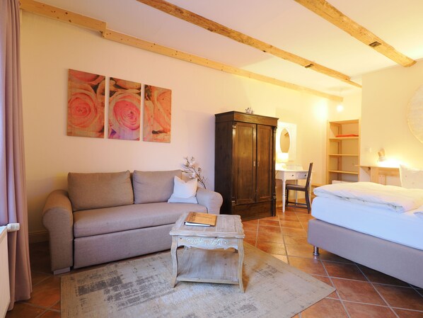 A cozy living room with a sofa, a small table, a cabinet, and a bed.