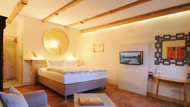 Un dormitorio con una cama, un sofá, una mesa y un espejo instalado en la pared.