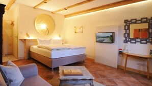 Un dormitorio con una cama, un sofá, un televisor y una mesa de madera.