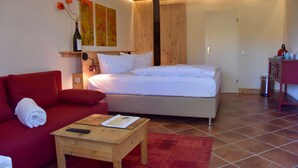 Un dormitorio con una cama, un sofá rojo, una mesa de madera y una alfombra roja.