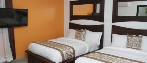 Habitación de hotel con dos camas, un televisor montado en la pared y una alfombra roja en el suelo.