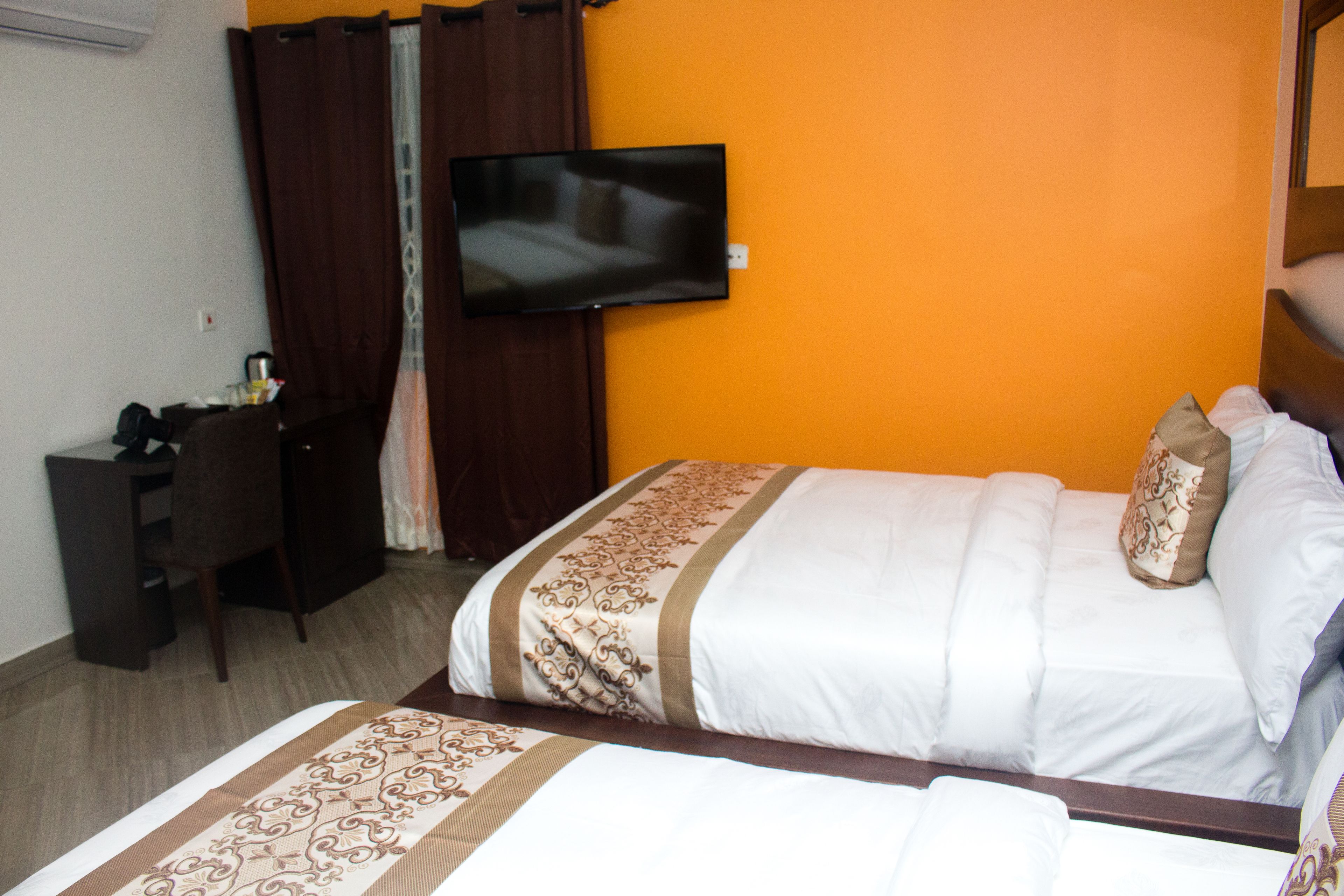 A hotel room with a bed, a television, a desk, and a wardrobe.