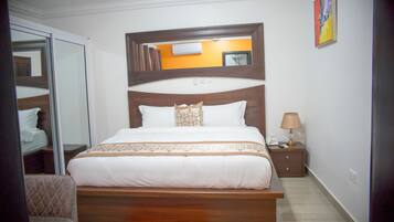 Una camera d'albergo con un letto grande, un comodino con una lampada e uno specchio sopra il letto.