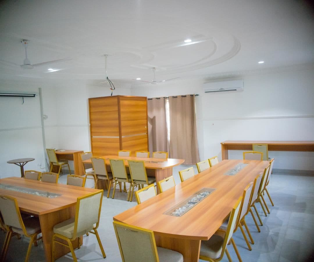 Ein Konferenzraum mit langem Tisch, Stühlen, einer Whiteboard und einer Holzwand.