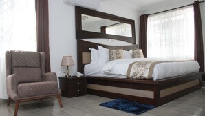 Een hotelkamer met een groot bed, een nachtkastje, een stoel en een blauw vloerkleed.
