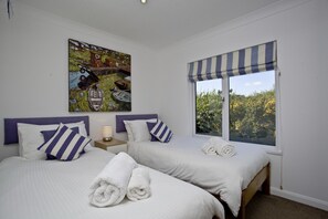 Habitación de hotel con dos camas, un cuadro en la pared, una ventana con persiana a rayas y toallas sobre las camas.