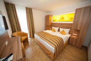A hotel room with a bed, a sofa, a TV, and a window with curtains. - Hotel zum Anker (Neumagen-Dhron)