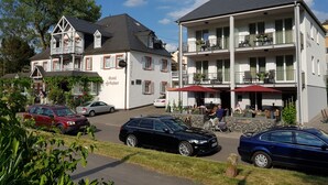 A hotel with a white facade, multiple balconies, and outdoor seating areas. - Hotel zum Anker (Neumagen-Dhron)