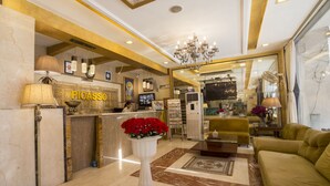 A lobby with a reception desk, a chandelier, a sofa, and a coffee table. - Hotel Picasso (New Delhi)