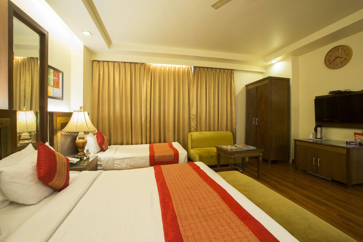 A hotel room with two beds, a desk, a chair, a television, and a wardrobe.