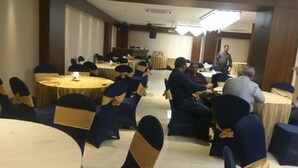A conference room with round tables and chairs, some with yellow sashes. - Hotel Picasso (New Delhi)