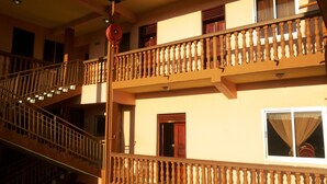 Un immeuble à plusieurs étages doté d’un balcon en bois, d’un enrouleur de tuyau d’incendie et d’un escalier.