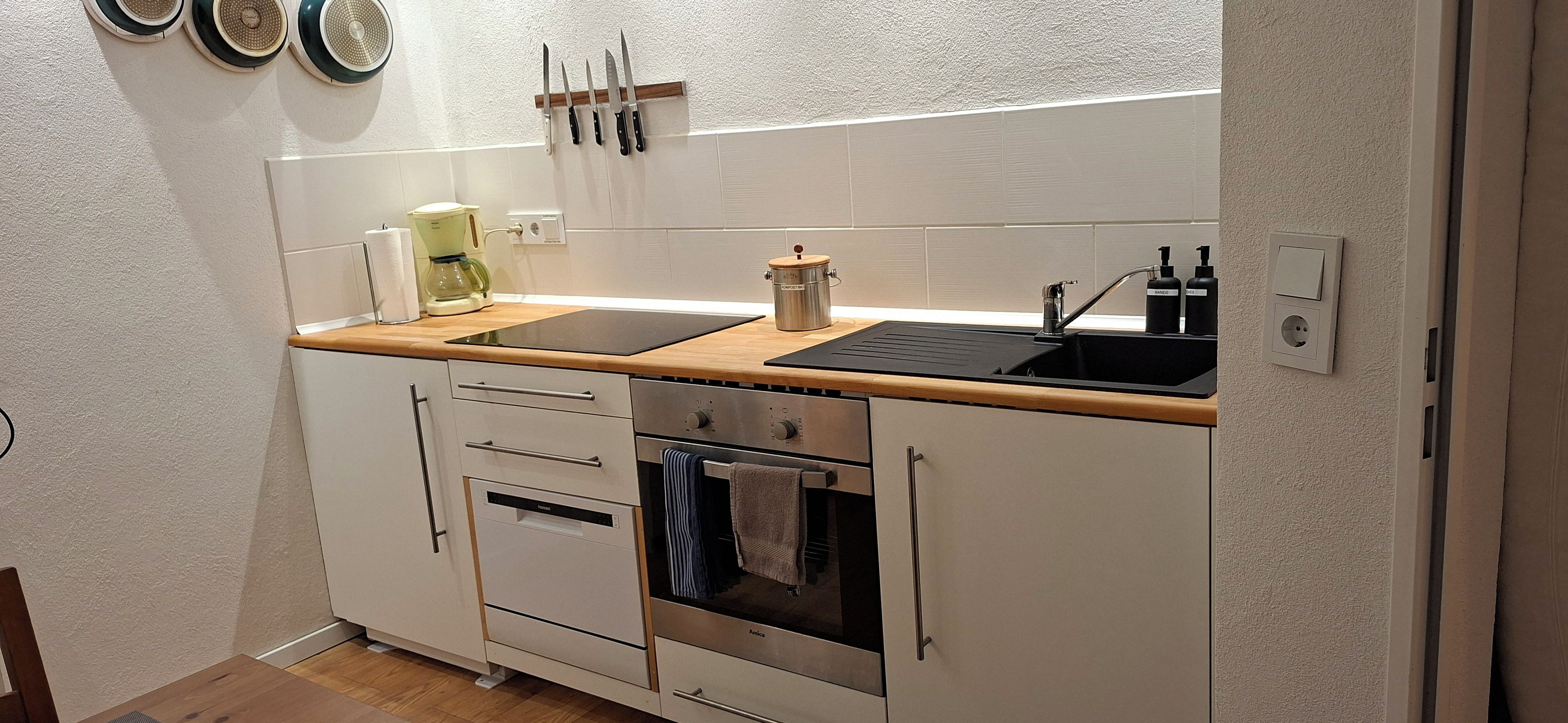 A compact kitchen with a sink, stove, oven, and a coffee maker.