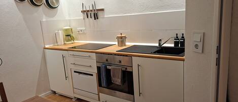 A compact kitchen with a sink, stove, oven, and a coffee maker.