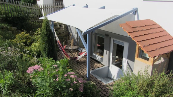 A house with a patio, a hammock, and a small shed.