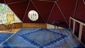A tent with a bed, a small table, and a chair. - Apple Dome at Cabot Shores Wilderness Resort (Englishtown)