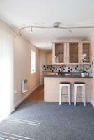 Una cocina moderna con una isla central, dos taburetes de bar y un ventanal que proporciona luz natural.