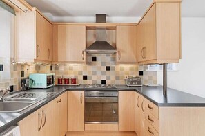 Une cuisine compacte avec des meubles en bois, un four à micro-ondes, un grille-pain et une cuisinière.