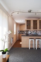 Una cocina moderna con armarios de madera, encimera negra y dos taburetes blancos.