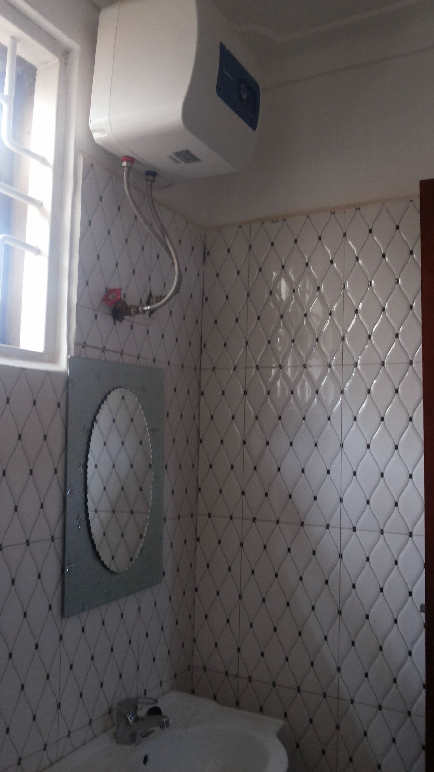 Ein Badezimmer mit einem weißen Waschbecken, einem Spiegel und einem Wandheizkörper.