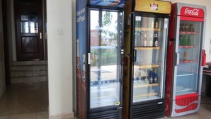 Três máquinas de bebidas automáticas com frente de vidro transparente, uma identificada com 'Bell' e a outra com 'Coca-Cola'.