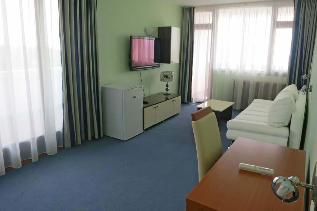 A hotel room with a bed, a desk, a chair, a television, and a small cabinet.