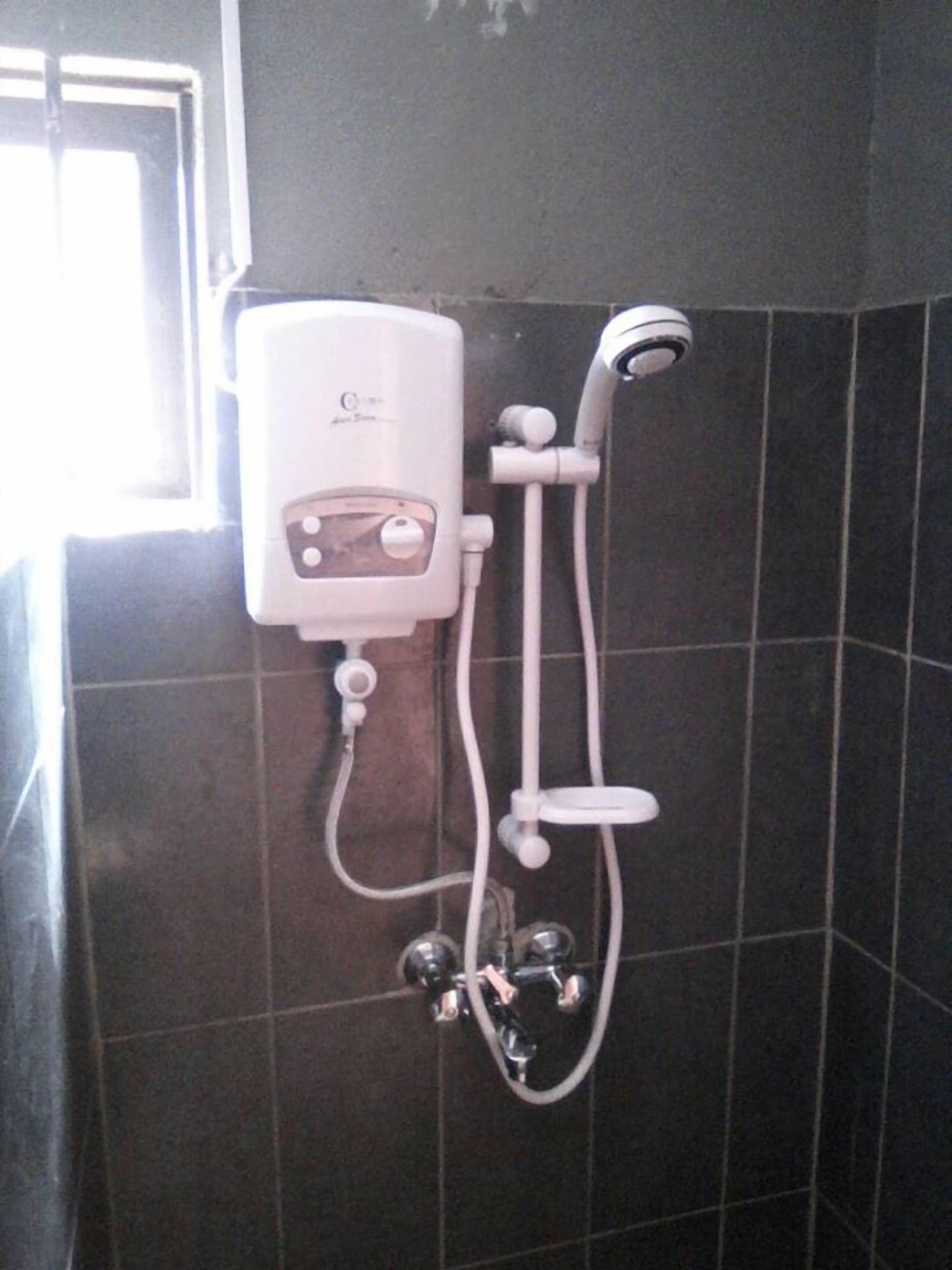 Een badkamer met een witte, handzwaaiende douchekop die aan de muur is bevestigd, met een bedieningsunit.