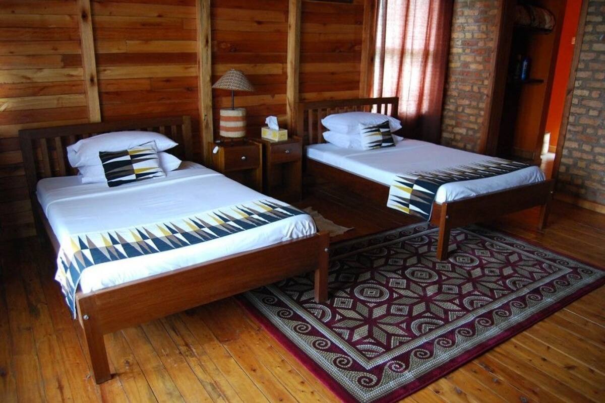 Quarto com duas camas de madeira, um tapete estampado e uma parede de madeira.