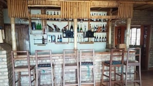 A bar area with wooden chairs and a bar counter displaying various bottles. - Rihuja Safari Lodge (Bwindi)