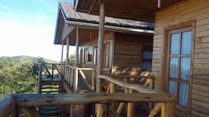 A wooden cabin with a porch and a staircase leading to the upper level.