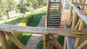 A wooden staircase leading down to a garden area with a stone pathway and greenery. - Rihuja Safari Lodge (Bwindi)
