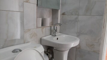 Un baño con un lavamanos blanco, un espejo encima y un inodoro con tapa.