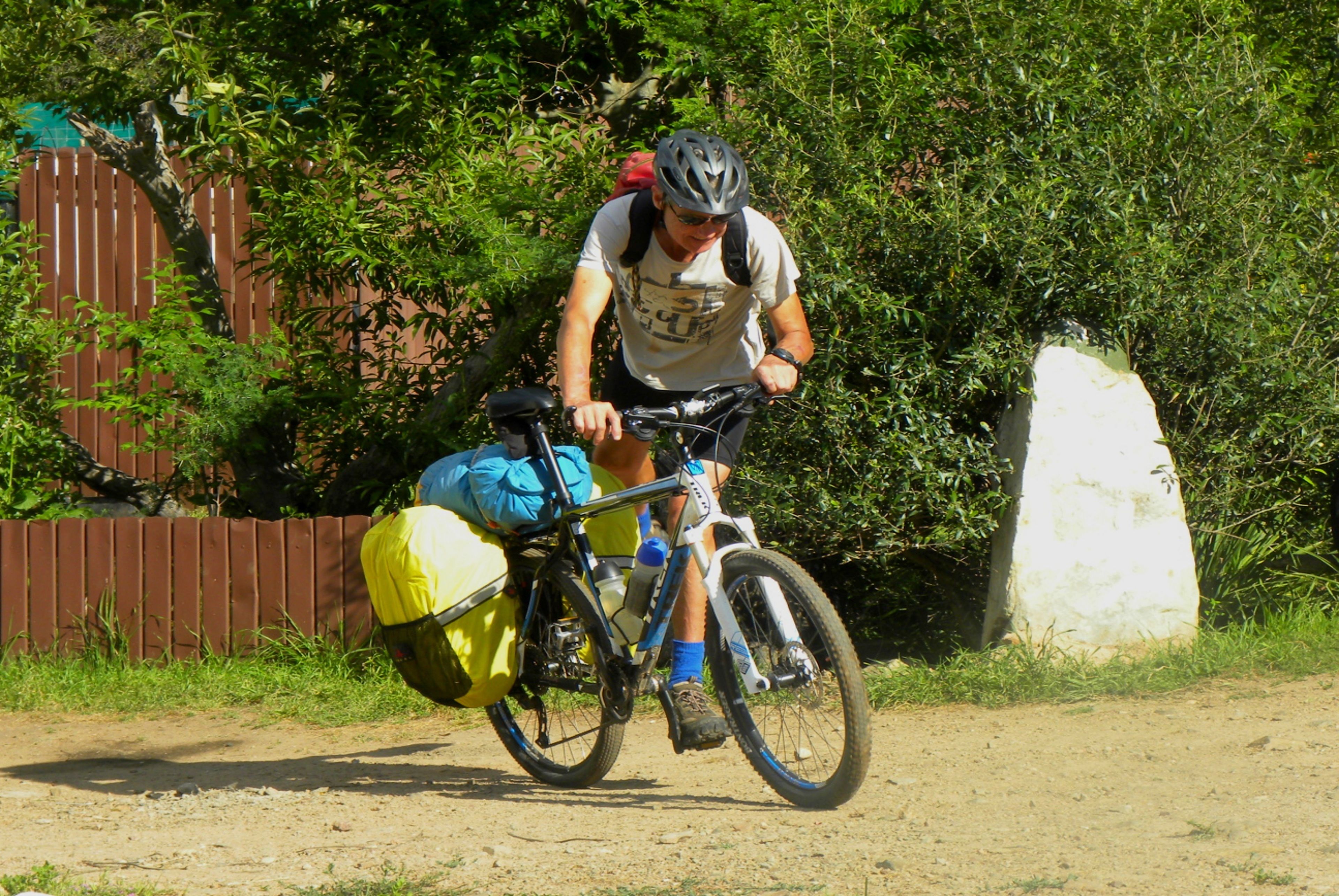 A person riding a bicycle with a backpack and a yellow bag on the back.