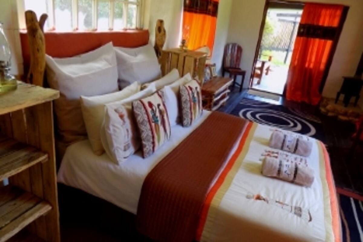 A bedroom with a large bed, a wooden nightstand, a desk, and a chair.