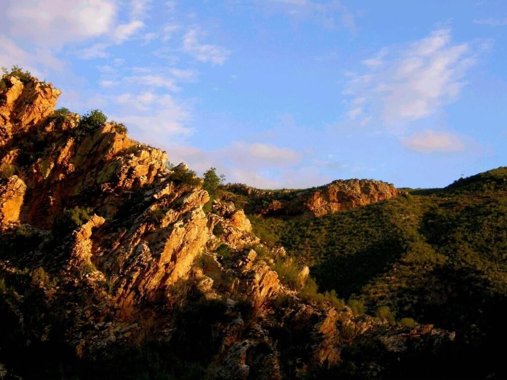 A rugged mountainous landscape with rocky cliffs and sparse vegetation.