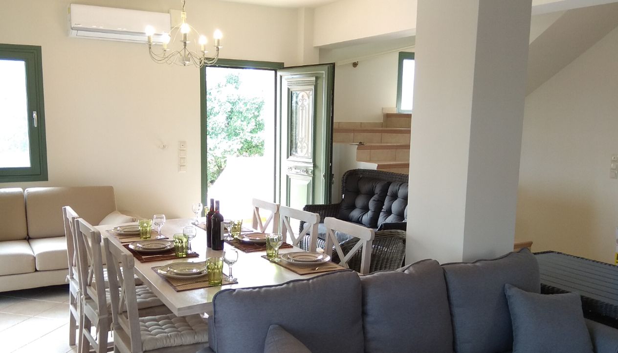 A dining area with a table set for four, a sofa, and a chair.