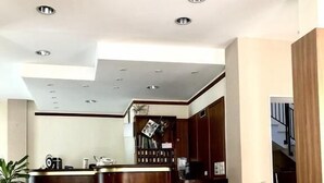 A modern living room with two grey sofas, a patterned rug, and a kitchen area in the background. - Hotel Europa (Nocera Umbra)