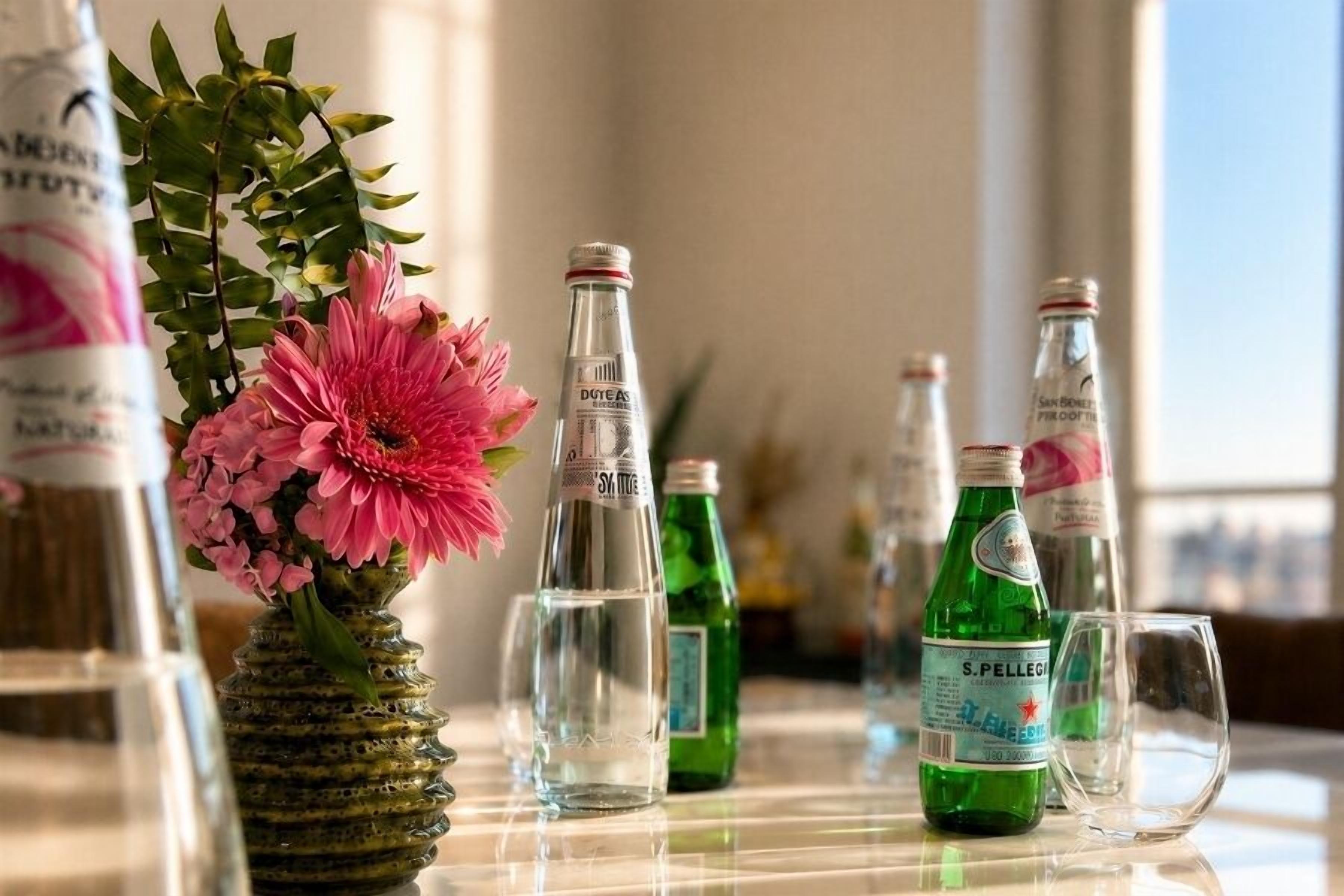 Een tafel met flessen en een bloevas.
