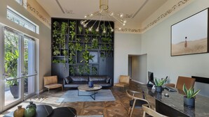 A modern living room with a leather sofa, a dining table with chairs, and a large wall of greenery. - Bachar House - FATTAL COLORS (Tel Aviv)