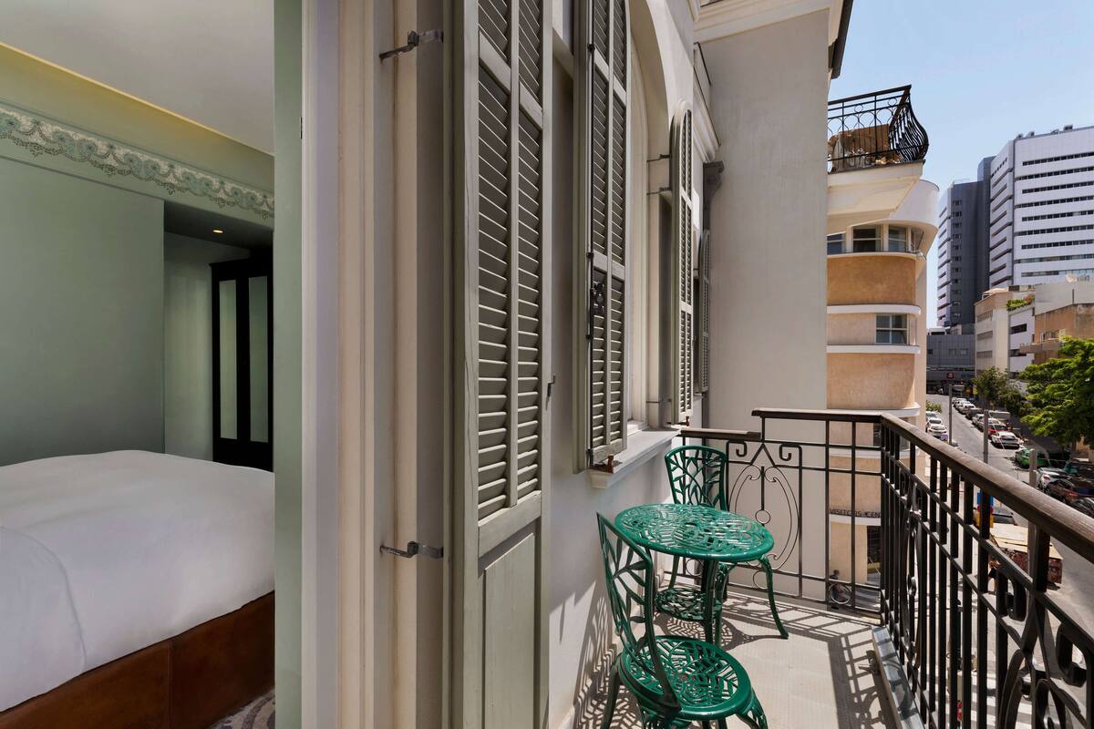 A balcony with a bed, a table, and chairs.