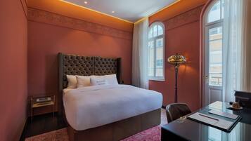 A hotel room with a large bed, a desk, and a lamp.